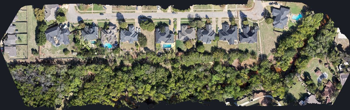 Top-down orthophoto of a distribution line easement with homes, fences and tree canopy